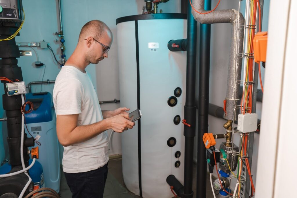 HVAC field service technician inspecting a boiler room with a mobile device